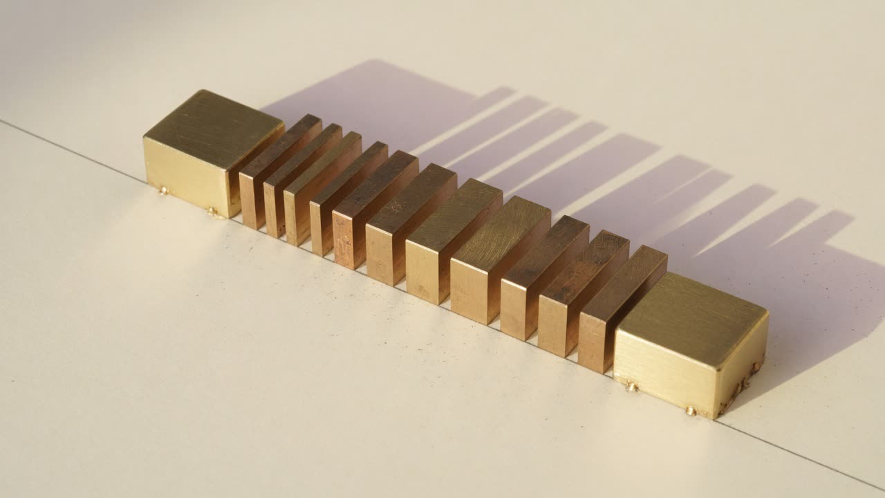 Row of brass bars between two brass end blocks on ivory paper